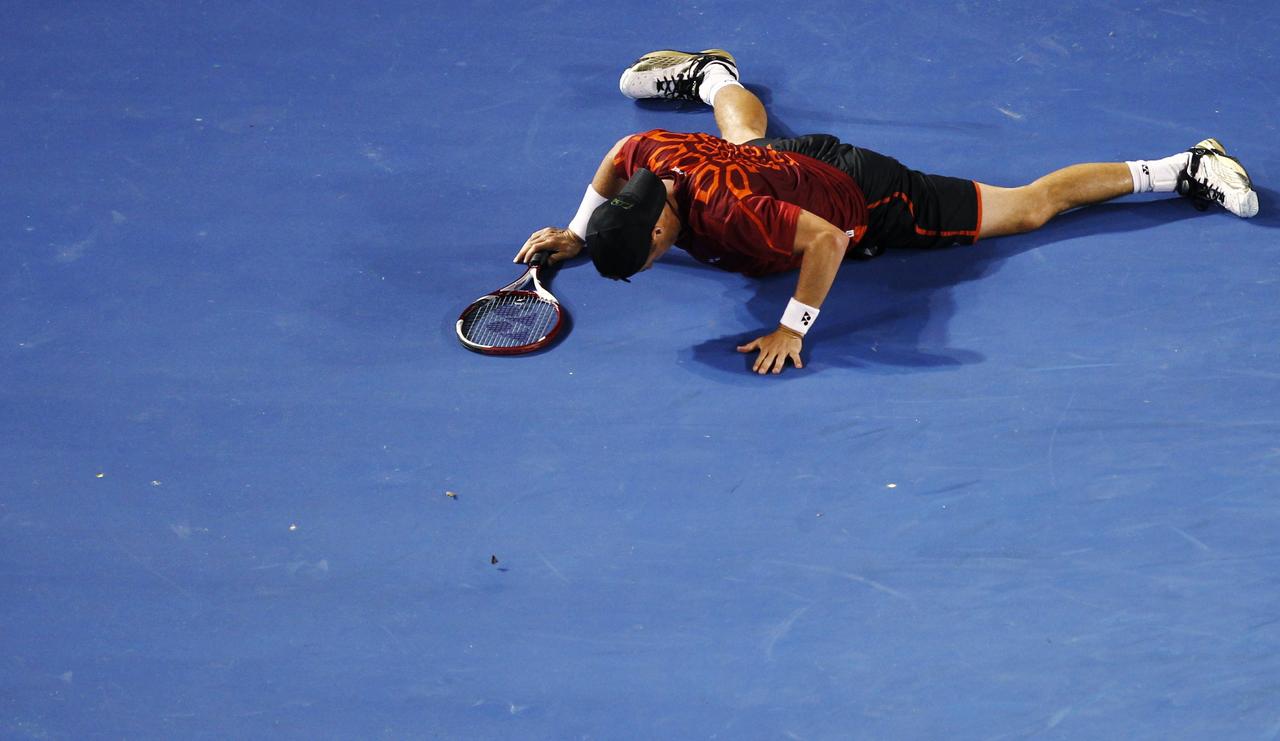 Lleyton Hewitt of Australia falls down after returning a shot to Novak Djokovic of Serbia during their men's singles match at the Australian Open tennis tournament in Melbourne January 23, 2012. REUTERS/Mark Blinch (AUSTRALIA - Tags: SPORT TENNIS) [Mark Blinch]