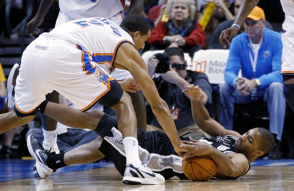 Oklahoma City Thunder guard Thabo Sefolosha (2) and San Antonio Spurs guard Gary Neal, right, reach for the ball in the third quarter of an NBA basketball game in Oklahoma City, Sunday, Jan. 8, 2012. Oklahoma City won 108-96. (AP Photo/Sue Ogrocki) [Sue Ogrocki]