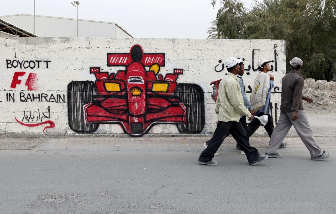 Men walk past anti-Formula One graffiti in the village of Barbar, west of Manama April 5, 2012. Former world champion Damon Hill has called on Formula 1 bosses to reconsider going ahead with this month's controversial Bahrain Grand Prix and warned that the sport's image could suffer if the race is held. The graffiti reads, "Boycott F1 in Bahrain, you will race on the blood of martyrs." REUTERS/Hamad I Mohammed (BAHRAIN - Tags: CIVIL UNREST POLITICS SPORT MOTORSPORT) [Hamad I Mohammed]