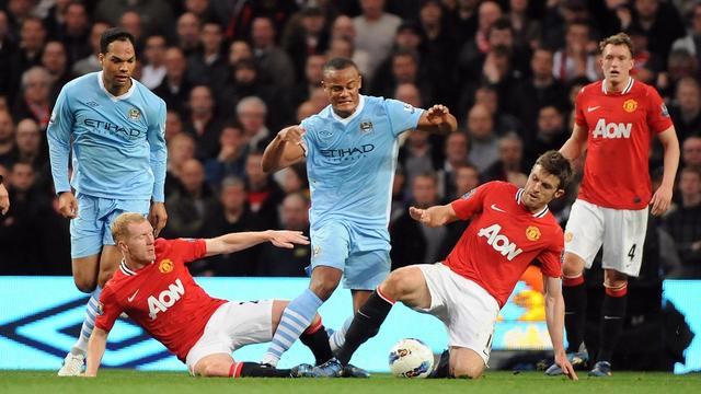 epa03201821 Manchester City's Vincent Kompany (C) vies for the ball with Manchester United's Paul Scholes (L) and Michael Carrick (R) during the English Premier League soccer match at the Etihad Stadium, Manchester, Britain, 30 April 2012. EPA/PETER POWELL DataCo terms and conditions apply. http//www.epa.eu/downloads/DataCo-TCs.pdf [KEYSTONE - Petter Powell]