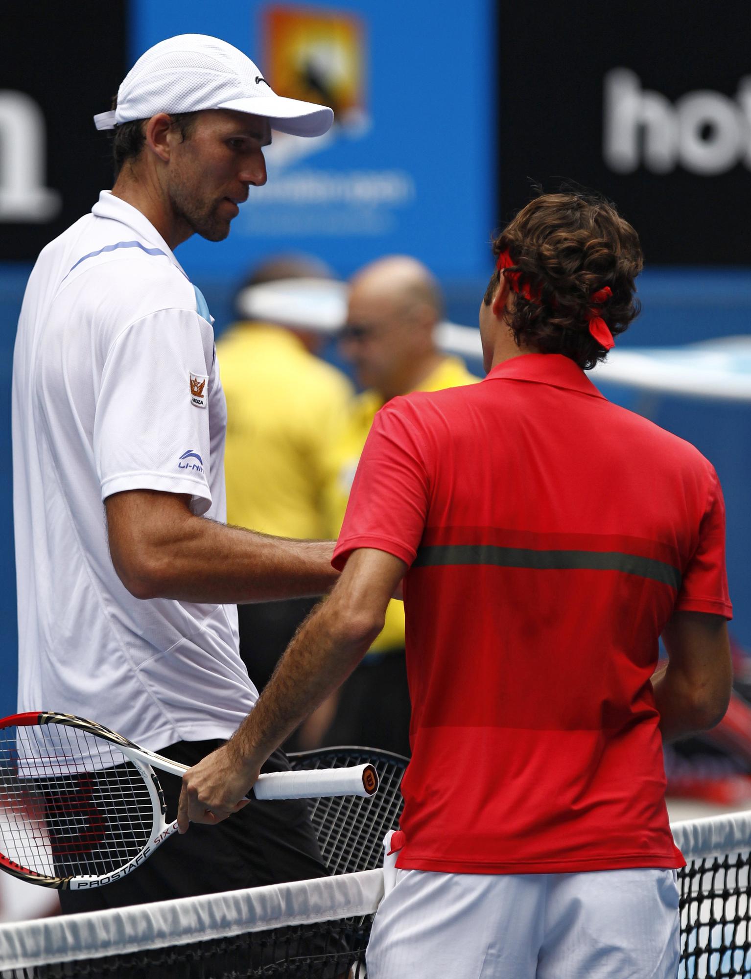 Roger Federer of Switzerland shakes hands with Ivo Karlovic of Croatia (L) after their men's singles match at the Australian Open tennis tournament in Melbourne January 20, 2012. REUTERS/Mark Blinch (AUSTRALIA - Tags: SPORT TENNIS) [REUTERS - Blinch]