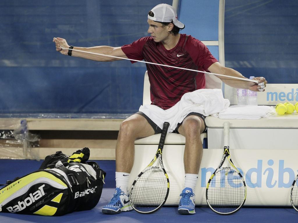 Spain's Rafael Nadal prepares tape for his racket handle during a practice session for the Australian Open tennis championship, in Melbourne, Australia, Friday, Jan. 13, 2012. (AP Photo/Mark Baker) [Mark Baker]