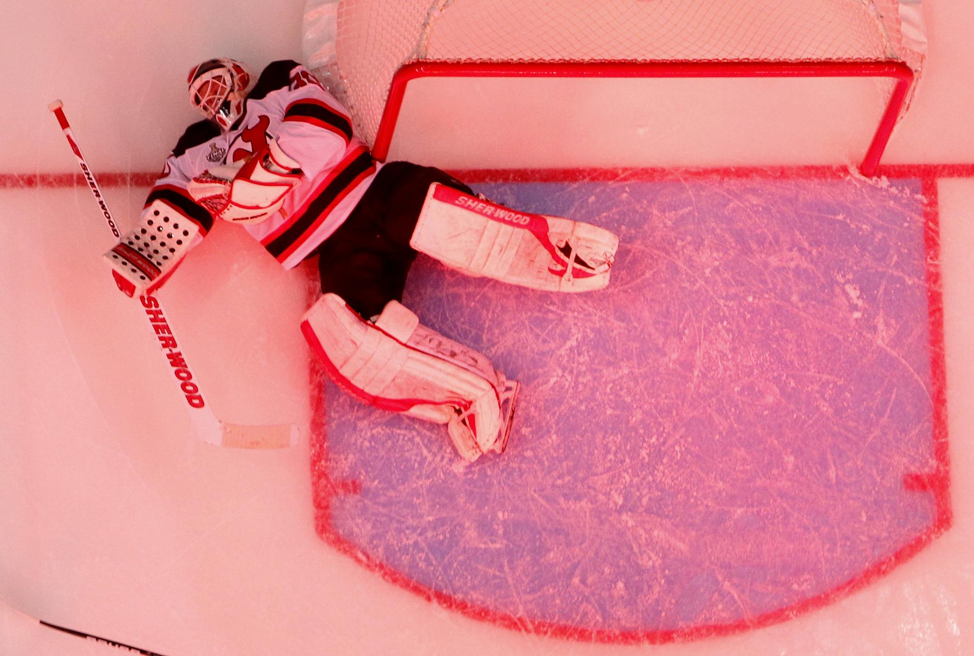 New Jersey Devils Martin Brodeur lays on the ice after Los Angeles Kings Jeff Carter scored during the third period in Game 3 of the NHL Stanley Cup hockey finals in Los Angeles, June 4, 2012. This picture is tinted red due to the spotlights turned on after a Kings goal. REUTERS/Danny Moloshok (UNITED STATES - Tags: SPORT ICE HOCKEY) [Danny Moloshok]