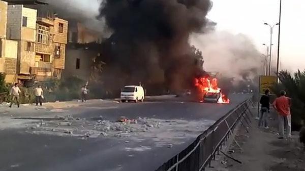 Cette image extraite d'une vidéo fournie par Shaam News Network montre une voiture incendiée dans la banlieue de Damas. [Shaam News Network]
