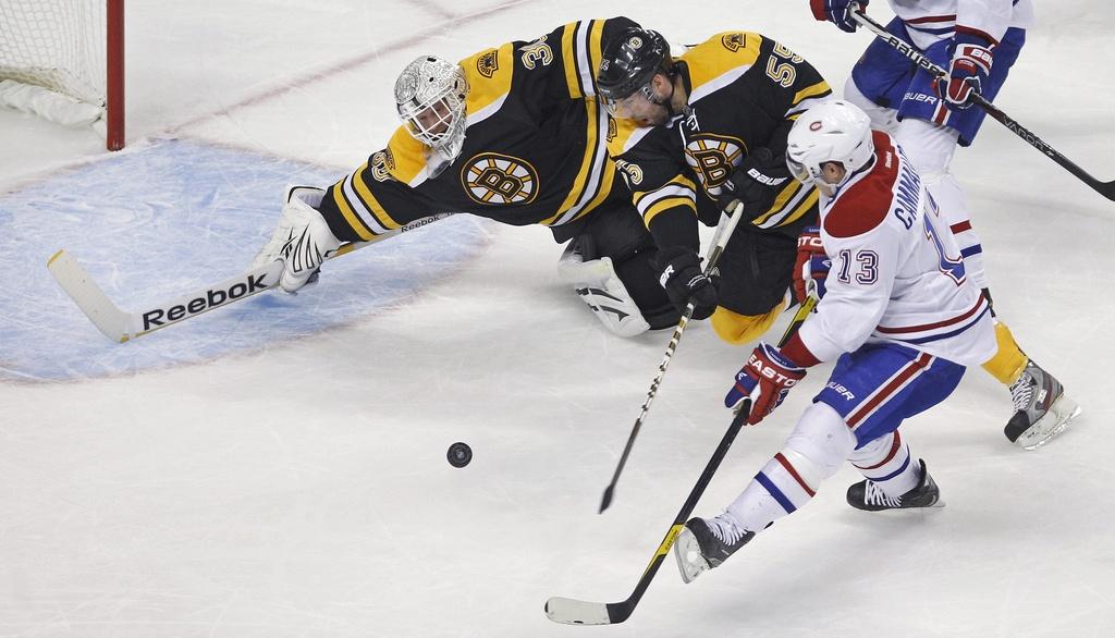 Boston Bruins goalie Tim Thomas (30) starts to dive to make a save on a shot by Montreal Canadiens left wing Mike Cammalleri (13) in the first period of an NHL hockey game in Boston, Thursday Jan. 12, 2012. At center is Bruins defenseman Johnny Boychuk (55). (AP Photo/Charles Krupa) [Charles Krupa]