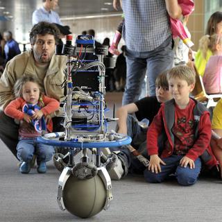 Des visiteurs observent un robot en équilibre et qui se déplace sur un ballon, lors du Festival de Robotique organise par l'EPFL, le 5 mai 2012 à Lausanne. [KEYSTONE - Martial Trezzini]