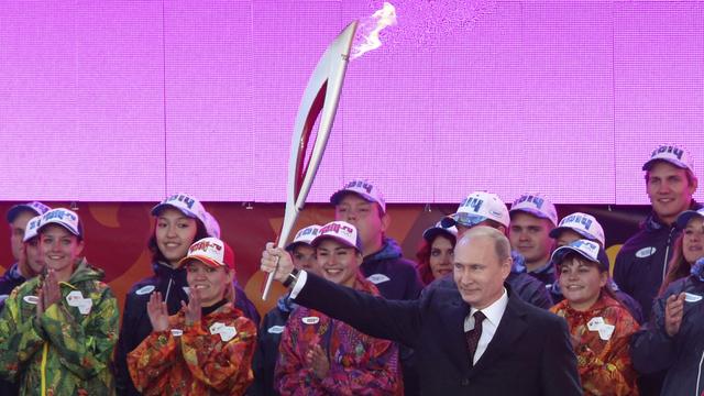 Le président russe Vladimir Poutine brandit la torche olympique à l'occasion du départ du relai de la flamme à Moscou le 6 octobre 2013. [Sergeï Karpukhin]