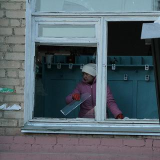 Une femme en train de dégager les débris de sa fenêtre après la chute de météorites en Russie, le 15 février 2013. [AP/Yevgenia Yemelyanova]
