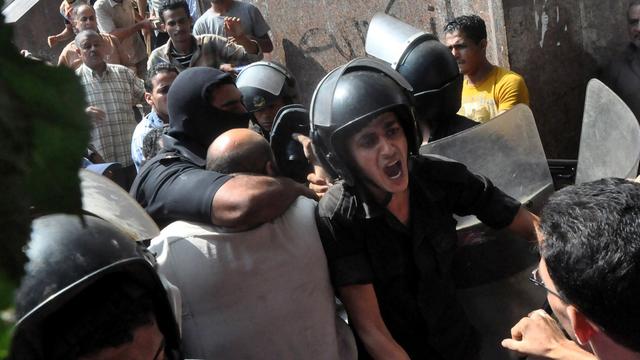 Les forces de sécurité égyptiennes escortant samedi des pro-Morsi hors de la mosquée cairote de al Fatah. [AP Photo/Hussein Tallal]