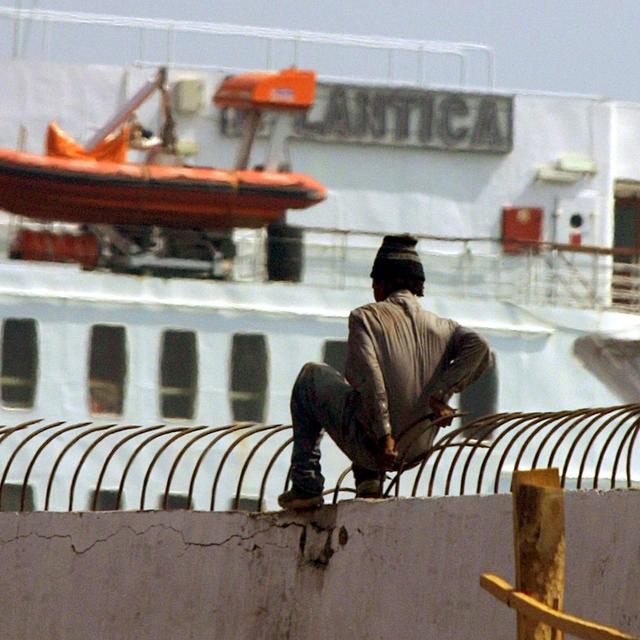 Un candidat à l'immigration escalade le mur du port de Tanger pour tenter de se glisser sous le châssis d'un semi-remorque qui le transportera vers l'Europe. [Abdelhak Senna]