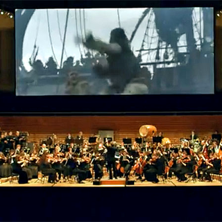 Un orchestre et un chœur de 120 musiciens et chanteurs pour interprètent la musique en direct en dessous de l'écran. [saisonculturelle.ch]