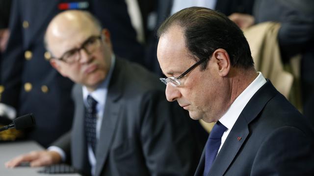 Le président français François Hollande et son ministre des Finances Pierre Moscovici (en arrière-plan). [Charles Platiau]