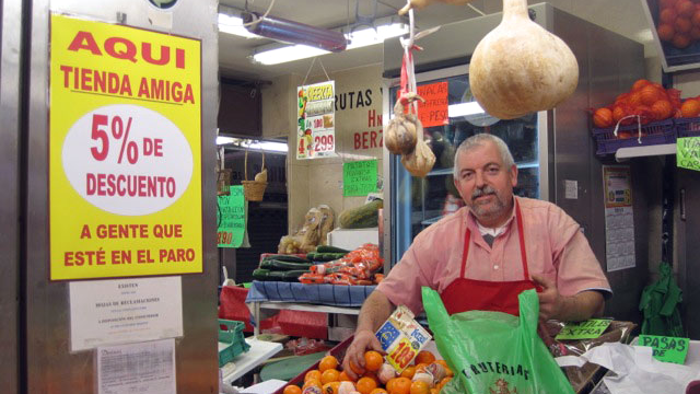 Jose Luis, marchand de fruits et légumes, avec l’affiche “Soy tienda amiga” (je suis une boutique amie).