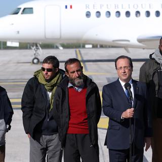 Le président français François Hollande entouré des quatre ex-otages à leur arrivée à l'aéroport de Villacoublay, à côté de Paris le 30 octobre 2013. [Kenzo Tribouillard]