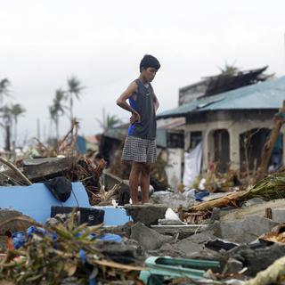 Un jeune garçon sur les ruines de sa maison à Tacloban, aux Philippines. [AP Photo/Wally Santana]