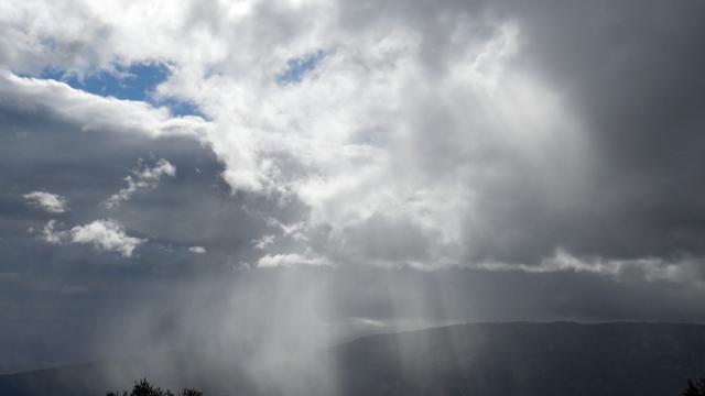 Un rayon de soleil traverse l'épaisse couche nuageuse au dessus du Salève, près de Genève. [Nicole Bougantouche]