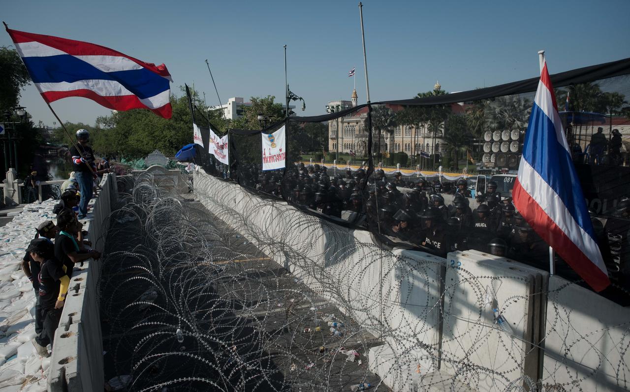 Les opposants au gouvernement thaïlandais font face à face avec la police ce dimanche 1er décembre à Bangkok. [AFP - Nicolas ASFOURI]