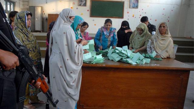 A police officer stands guard as staff count ballots at a polling station during parliamentary elections in Islamabad, Pakistan, 11 May 2013. Polls in Pakistan's election closed at 6:00 pm (1300 GMT) on 11 May, the election commission said. Preliminary results were to trickle in a few hours later. EPA/W. KHAN [W. Khan EPA]