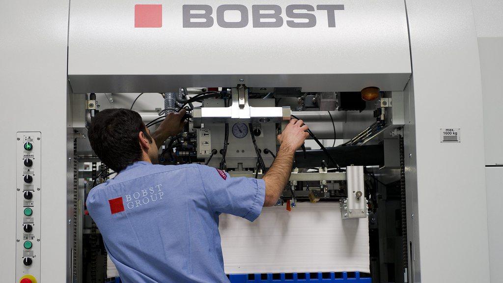 Un employé de Bobst travaillant sur une machine sur le site de production a Mex (VD). [Jean-Christophe Bott]