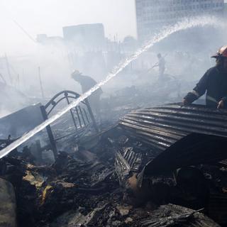 Dimanche 3 février: des pompiers s'activent dans les décombres causés par un incendie qui a ravagé un bidonville de Dacca, au Bangladesh. [Abir Abdullah]