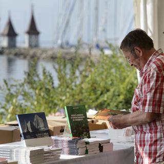Un homme lit un livre sur fond de Lac Léman lors de la 3e édition de Livre sur les quais en septembre 2012 à Morges. [Laurent Gillieron]