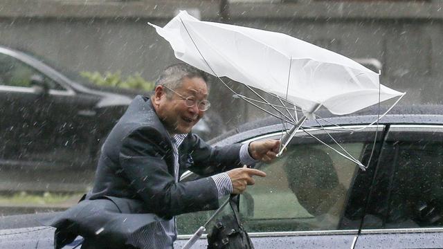 epaselect epa04434077 A businessman is struggling with his umbrella broken by wind, against heavy rain in Tokyo, Japan, 06 October 2014. Typhoon Phanfone is hitting through southwestern, western and central Japan with heavy rain and strong winds after lashing western and southern Japan, leaving two dead and three missing. Hundreds of thousands of people were advised to evacuate their homes with the Japan Meteorological Agency warning of mudslides, heavy rains, swollen rivers and strong winds in wide areas of the country. EPA/KIMIMASA MAYAMA [KIMIMASA MAYAMA]