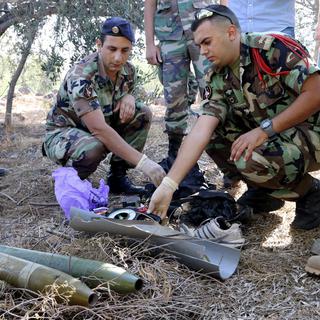 Un soldat de l'armée libanaise inspecte des fragments de roquette, qui aurait été lancée depuis El Mari au Liban. [Karamallah Daher]