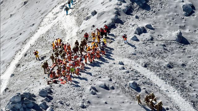 Les secours continuent à parcourir le paysage lunaire du volcan. [AP Photo/Kyodo News]