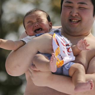Samedi 26 avril: un sumo tient un bébé qui a participé à un concours de cris de bébés dans le temps de Senso-Ji à Tokyo, une cérémonie rituelle de prières pour qu'ils grandissent sans être malades. [AP Photo/Eugene Hoshiko]