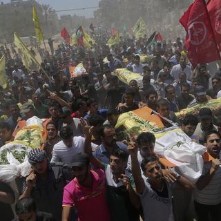 Des Palestiniens portent les corps de sept personnes tuées lors des raids. [AP Photo/Hatem Moussa]