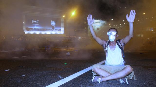 Un manifestant pro-démocratie lève les mains en signe de reddition sous les tirs de lacrymogènes des forces de l'ordre.