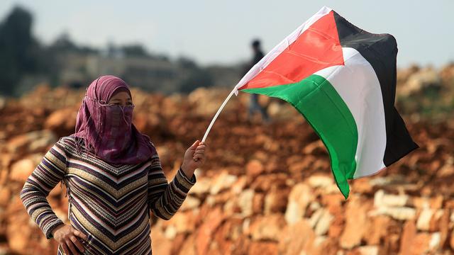 Une femme brandit un drapeau palestinien à Ramallah. [Issiam Rimawi/Anadolu Agency]