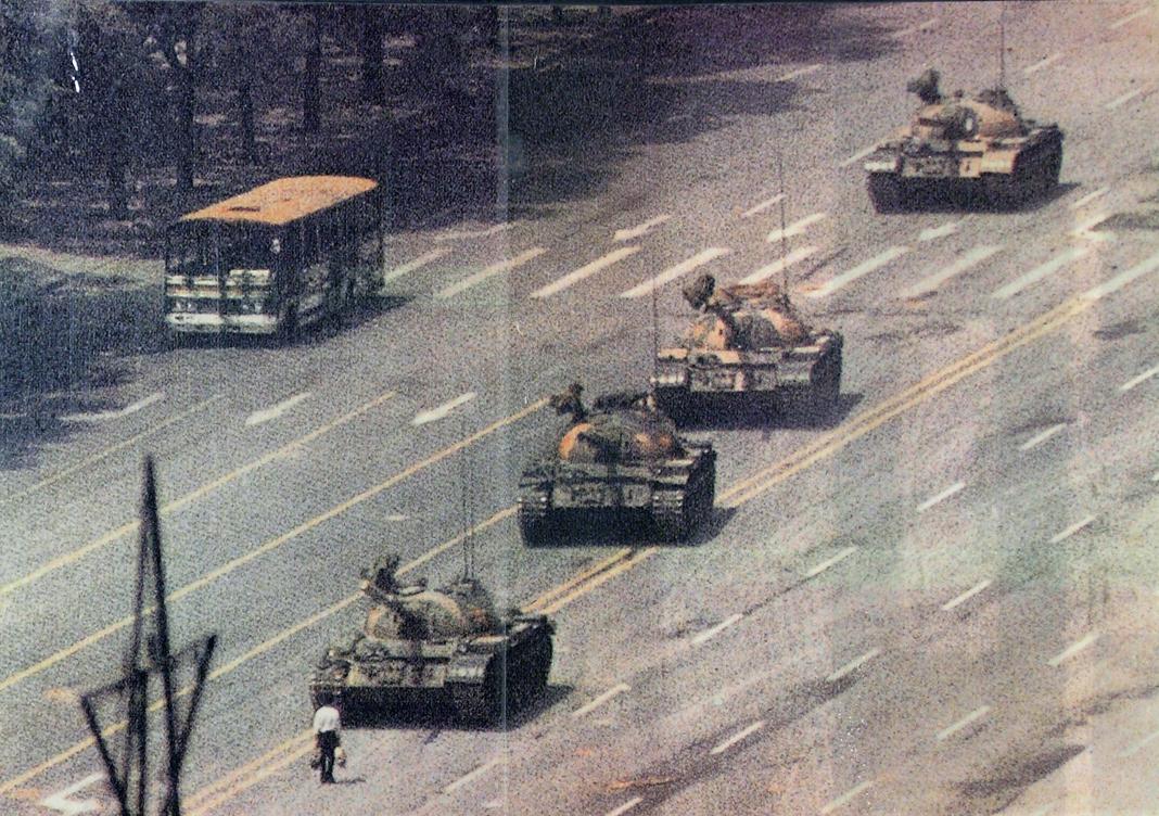 Le 5 juin 1989, alors que des tanks remontent l'avenue Changan pour rejoindre la place Tiananmen, un citoyen pékinois se place en opposition. Des photographes captent l'événement et la photo devient le symbole de Tiananmen. Personne ne sait son nom, ni ce qu'il est devenu. [64museum.org]