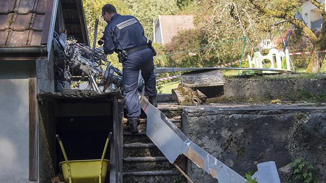 Un gendarme examine des débris de l'hélicoptère qui s'est écrasé jeudi près de Montbéliard. [Georgios Kefalas]