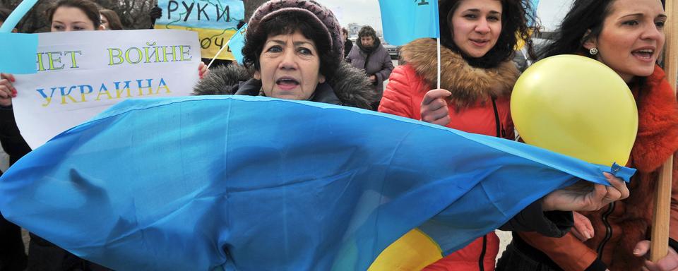 Des femmes brandissent le drapeau ukrainien et tatar de Crimée en scandant "Pas de guerre, nous sommes pour la paix", Simferopol le 8 mars 2014. [Genya Savilov]