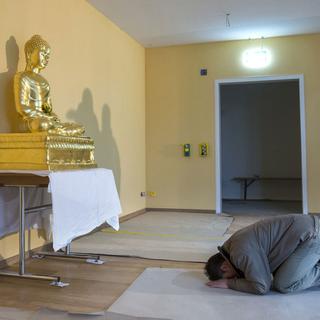 Un bouddhiste en prière dans la Maison des religions en pleine installation. Berne le 11 décembre 2014. [Keystone - Peter Klaunzer]