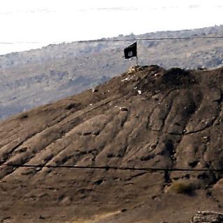 Un drapeau du groupe Etat islamique flotte sur la colline surplombant Kobané. [EPA/SEDAT SUNA]
