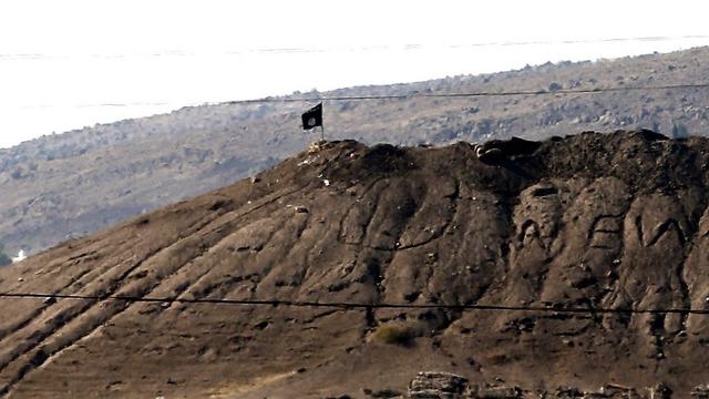 Un drapeau du groupe Etat islamique flotte sur la colline surplombant Kobané. [EPA/SEDAT SUNA]