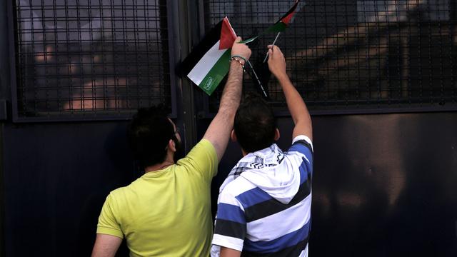 Pose d'un drapeau palestinien sur un fourgon de police. [AP Photo/Petros Karadjias]