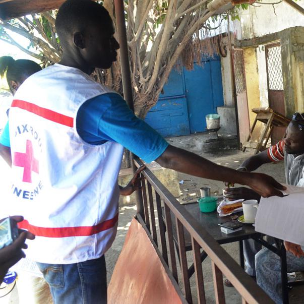 Un membre de la Croix rouge guinéenne distribuant des tracts d'information sur le virus Ebola. [Cellou Binani]