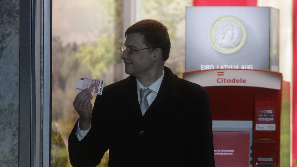 Le Premier ministre letton Valdis Dombrovskis tient un euro pour symboliser l'entrée de la Lettonie dans la zone euro. [EPA/Valda Kalinina]