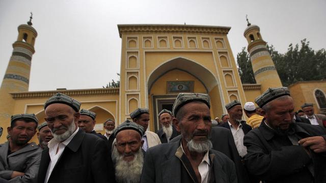 Des Ouïghoures devant la mosquée où a été tué l'imam. [EPA/HOW HWEE YOUNG]