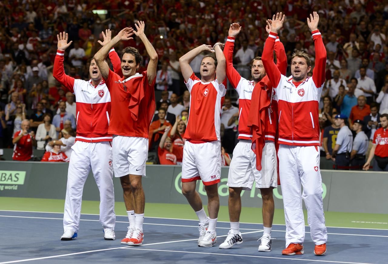 SWITZERLAND, Geneva : (L to R) Swiss tennis team Marco Chiudinelli, Roger Federer, Severin Luethi, Michael Lammer, and Stan Wawrinka gesture as they celebrate winning the Davis Cup semi-final between Switzerland and Italy on September 14, 2014 in Geneva. AFP PHOTO / FABRICE COFFRINI [Fabrice Coffrini]