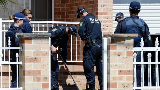 Des policiers passent une maison au détecteur de métaux, ce jeudi 18 septembre à Sydney. [DEean Lewins]