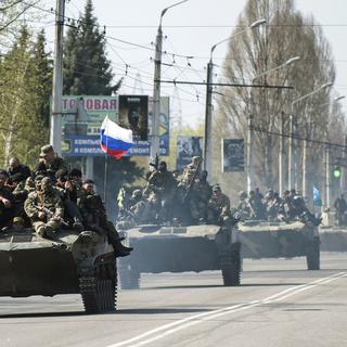 Une colonne de chars, dont certains arborent le drapeau russe, avancent sur la ville ukrainienne de Kramatorsk. [AP Photo - Evgeniy Maloletka]