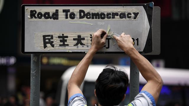 Un employé nettoie les derniers signes de la contestation populaire à Hong Kong, ce lundi 15 décembre 2014. [ISAAC LAWRENCE]