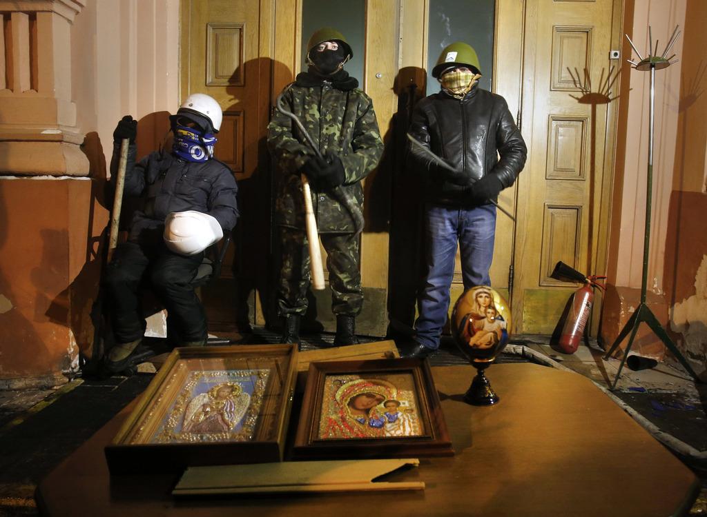 Des manifestants radicaux gardent l'entrée du ministère de la Justice lundi matin 27 janvier à Kiev. [KEYSTONE - AP Photo/Sergei Grits]