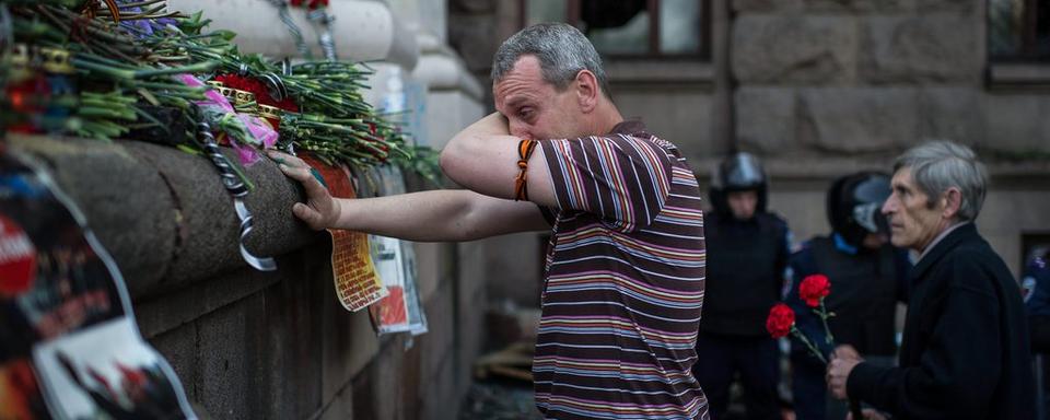 Un homme pleure après avoir déposé une fleur près du bâtiment incendié à Odessa le vendredi 2 mai et dans lequel une trentaine de militants pro-russes ont péri. [EPA/ALEXEY FURMAN]