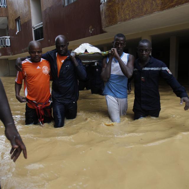 Firefighters evacuate a sick woman in a flooded area at Riviera Bounoumin in Abidjan June 29, 2014. REUTERS/Luc Gnago (IVORY COAST - Tags: DISASTER ENVIRONMENT) [Luc Gnago]