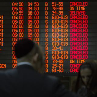 Des passagers devant le tableau affichant les départs depuis l'aéroport de Tel Aviv. [Siegfried Modola]